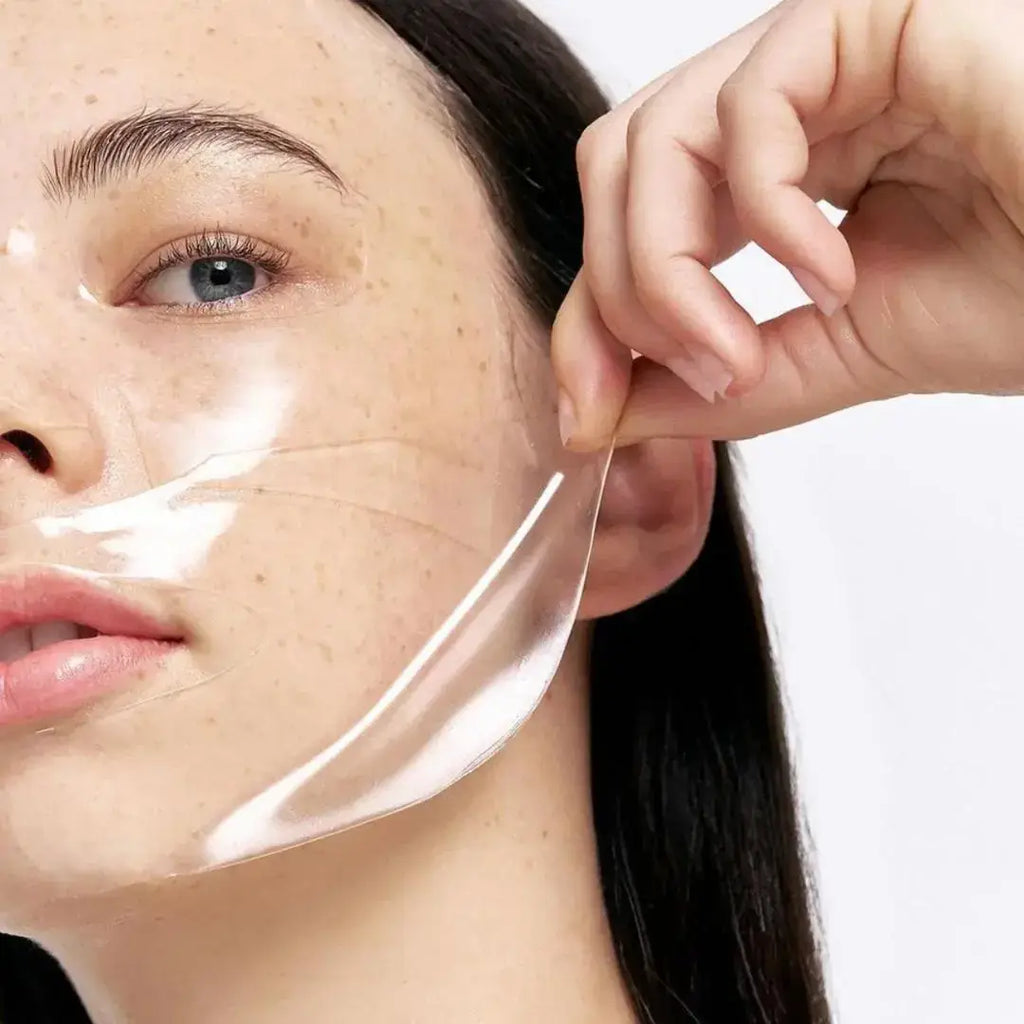 Kvinne som forsiktig fjerner en gjennomsiktig Bio-Collagen ansiktsmaske fra ansiktet sitt